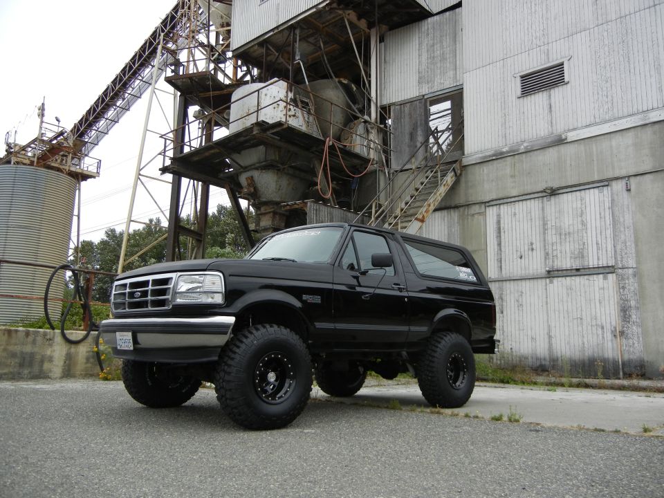 Black Ford Bronco with lifted suspension and off-road tires parked in front of an industrial building