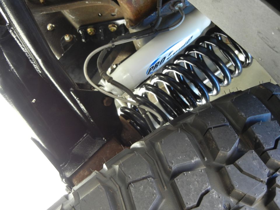 White Pro-Comp shock absorber and black coil spring with tire tread