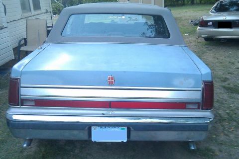 2000 Mercury Grand Marquis - Rear view of a light blue Lincoln Town Car with a vinyl top and Kansas license plate.