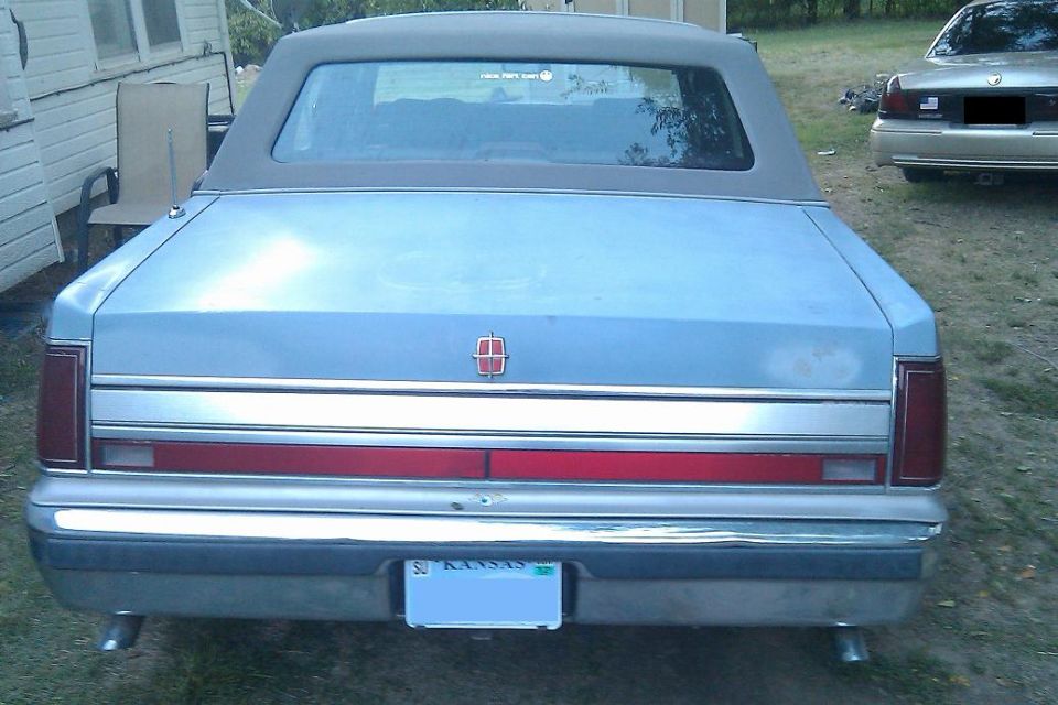 Light blue Lincoln Town Car rear, with a red and chrome trim strip, Kansas license plate, and a vinyl top