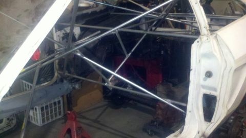 1978 Ford Mustang II - The interior of a vehicle is visible, a complex roll cage structure and a red seat.