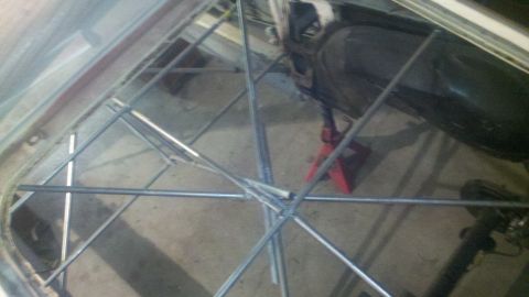 1978 Ford Mustang II - Metal scaffolding is erected inside a car's interior, with a red jack stand visible.
