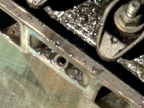 1982 Ford Bronco - A close-up view of a greasy engine component, showing water droplets on its surface.