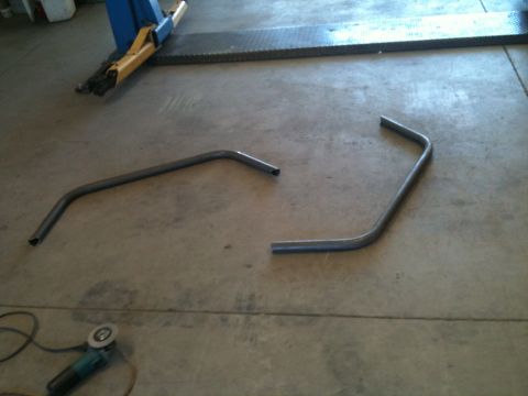 1966 Ford Bronco - Metal tubing and a grinder are on the floor of a workshop, possibly for fabrication or repair.
