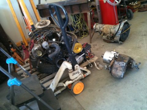 1966 Ford Bronco - Engine and transmission components are staged on a pallet jack in a garage setting.