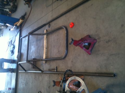 1966 Ford Bronco - Metal tubing and fabrication equipment are laid out on a concrete shop floor.