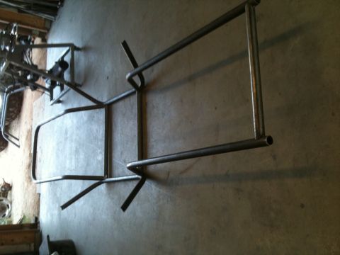 1966 Ford Bronco - A metal frame, possibly for a vehicle, lies on a concrete floor.