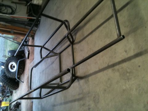 1966 Ford Bronco - A metal roll cage frame is shown lying on a concrete floor, with a tire visible in the background.