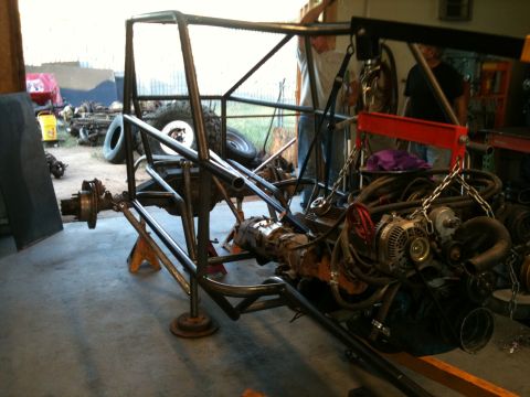 1966 Ford Bronco - A custom tube chassis is being assembled with an engine being lowered into place by a crane.