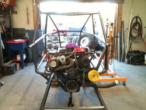 1966 Ford Bronco - Engine assembly on a stand in a garage with parts and tools in the background.