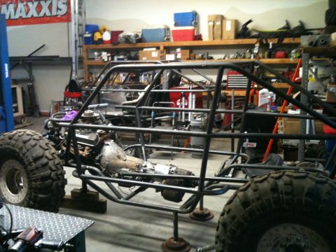 1966 Ford Bronco - A custom-built off-road buggy frame is shown with its engine and large tires in a workshop setting.