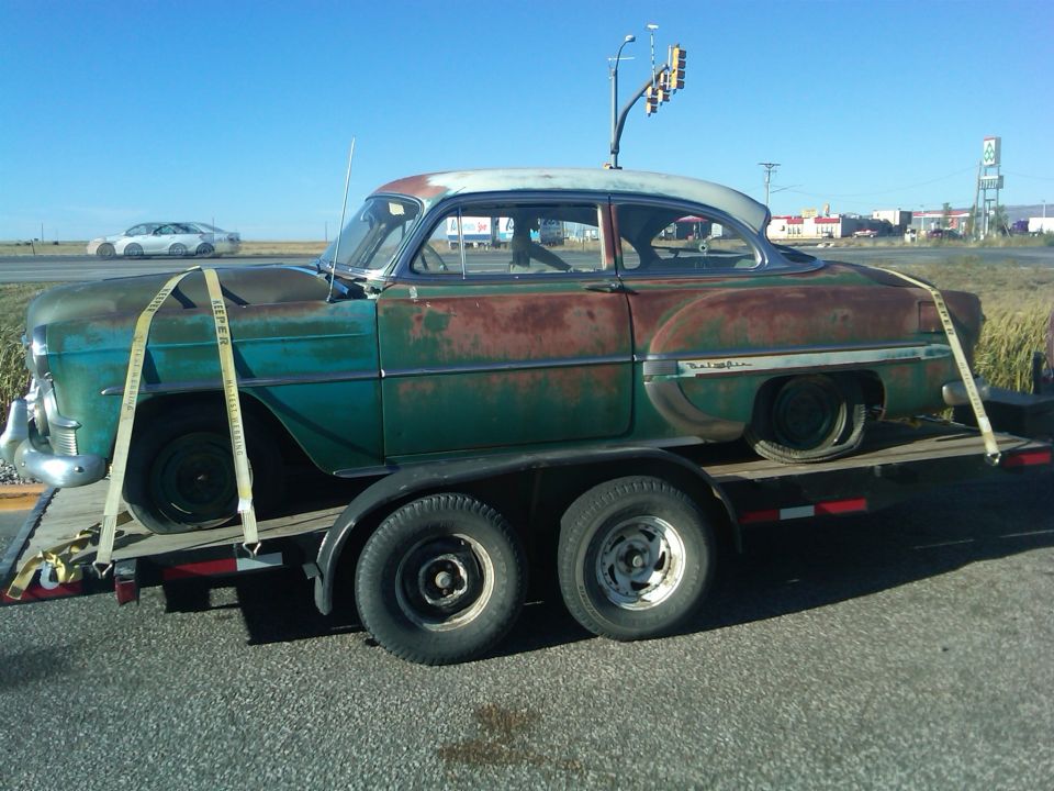 Rusty teal and white 1953 Chevrolet Bel Air on a trailer, side view