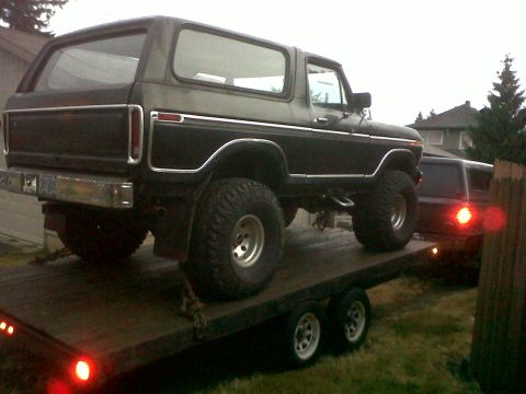 1979 Ford Bronco - A lifted Ford Bronco is loaded onto a trailer, with another vehicle visible behind it.