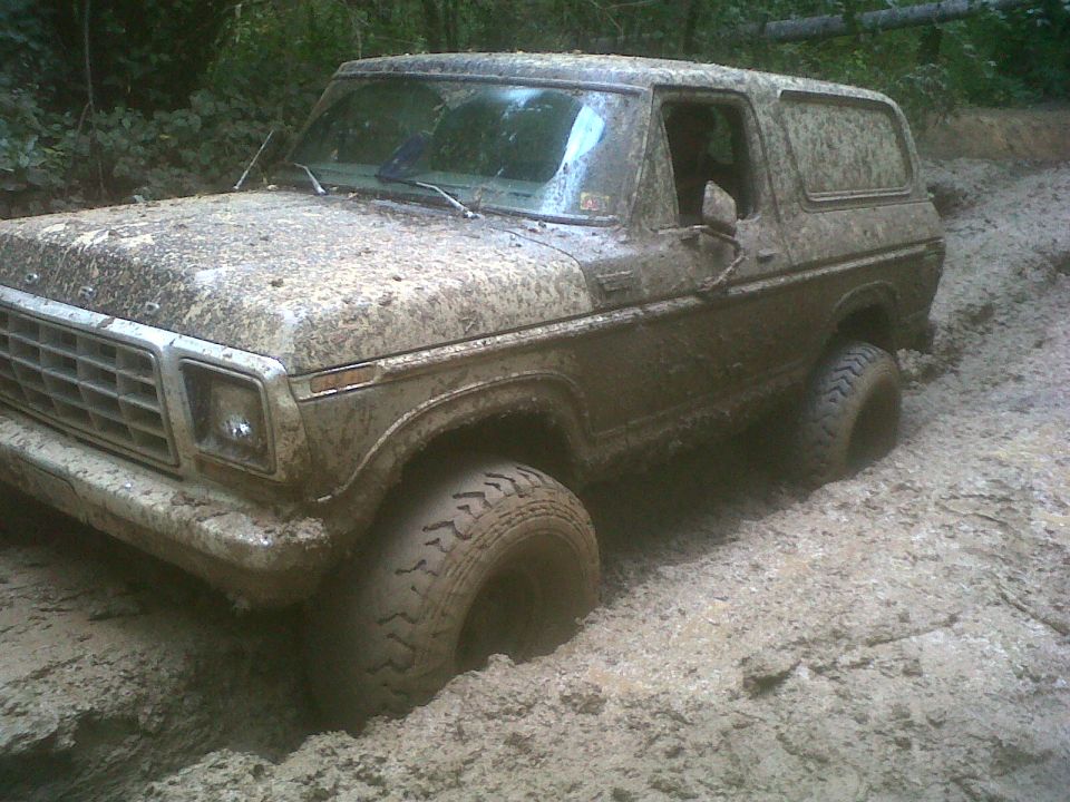 Mud-covered late-1970s Ford Bronco in a muddy trail