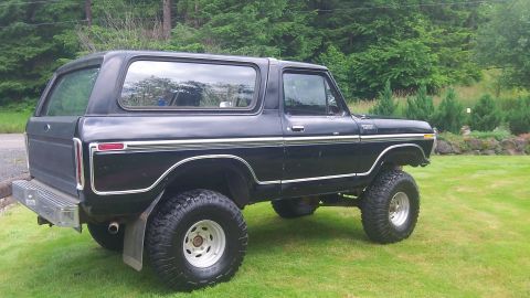 1979 Ford Bronco - This lifted black Ford Bronco is shown from a three-quarter rear view, parked on a grassy lawn.