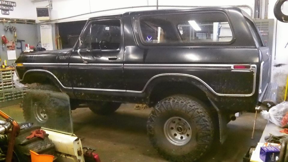 Black Ford Bronco with lifted suspension and large tires parked in a garage