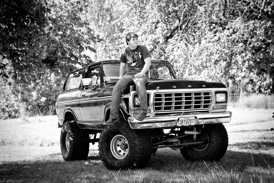 Lifted Ford Bronco on big tires with a man sitting on the fender, B&W