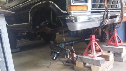 1979 Ford Bronco - Front axle assembly removed from a classic Ford truck, supported by jack stands for maintenance.
