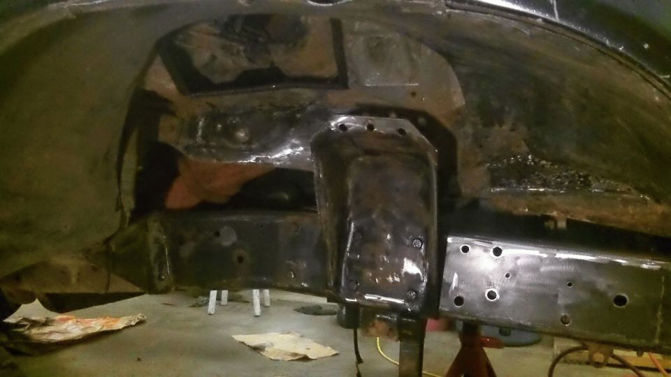 Blackened metal frame and suspension parts with visible welds and bolt holes