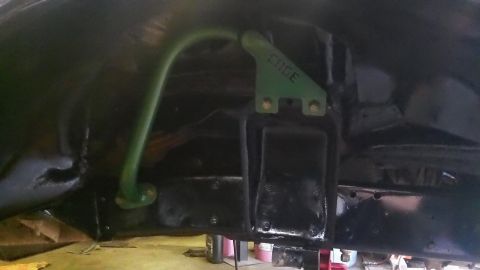 1979 Ford Bronco - Close-up view of the underbody showing a green sway bar and a bracket with visible text.