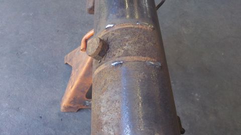 1979 Ford Bronco - This close-up shows a rusty, welded axle housing resting on an orange jack stand, indicating mechanical work.