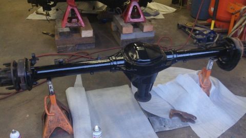 1979 Ford Bronco - A freshly painted black rear axle assembly is supported by jack stands in a workshop setting.