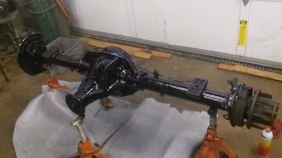 Black heavy-duty rear axle assembly on jack stands, possibly for a truck or large SUV