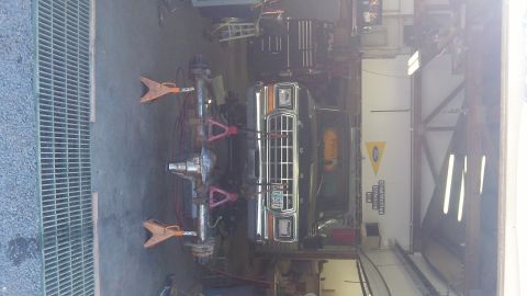 1979 Ford Bronco - A 1979 Ford Bronco is shown with its front end elevated on jack stands, indicating it is in a repair shop.