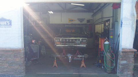 1979 Ford Bronco - 1979 Ford Bronco undergoing service with front end raised and axle removed in a garage.