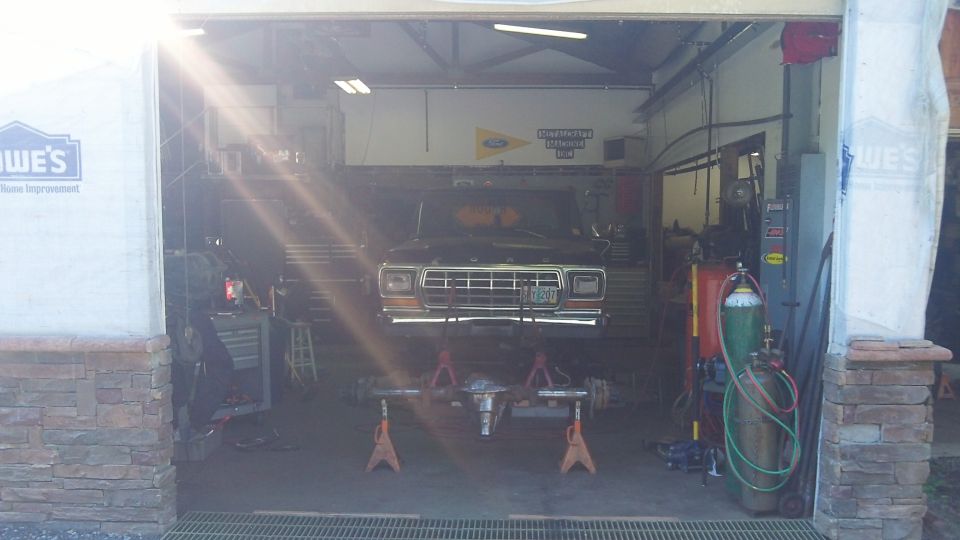 1979 Ford Bronco front end raised on jack stands in garage, front axle removed