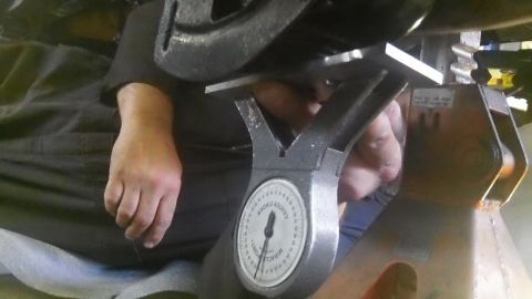 1979 Ford Bronco - A mechanic uses a gauge to measure a vehicle's suspension components while it's on jack stands.