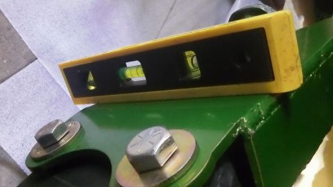 1979 Ford Bronco - A yellow spirit level is placed on a green metal component, with visible bolts and washers.