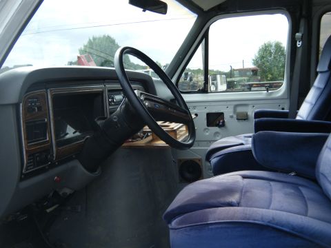 1988 Ford E350 - The interior of a 1988 Ford E350 van, a dashboard with wood trim and plush blue seats.