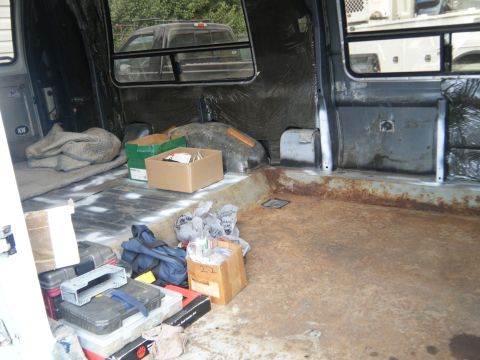 1988 Ford E350 - The interior of a van shows a cluttered cargo area with various items stored inside.