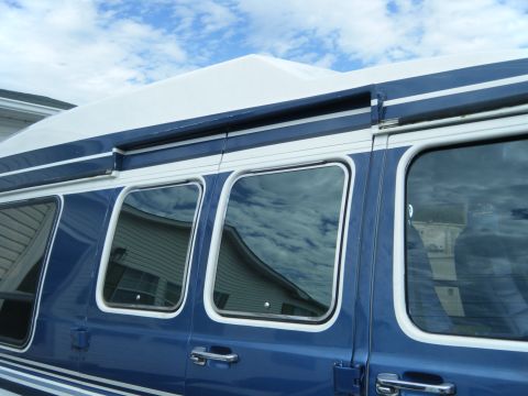 1988 Ford E350 - Side profile of a blue and white 1988 Ford E350 van under a cloudy sky.
