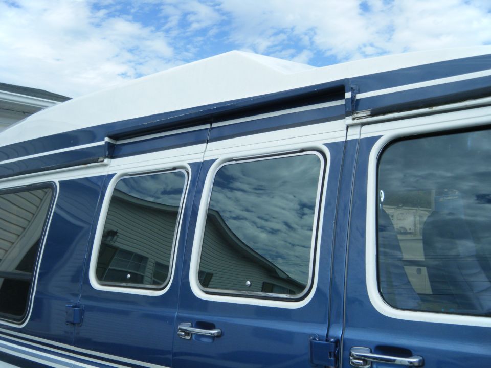 Side view of a blue and white 1988 Ford E350 van with multiple windows