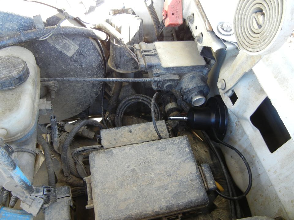 Close-up of engine bay with fuse box, wiring, and brake booster