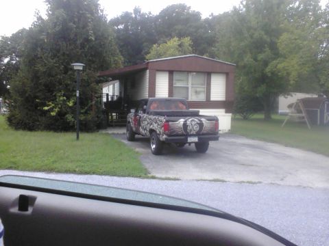 1988 Ford Bronco - Rear view of a customized pickup truck parked in front of a mobile home.