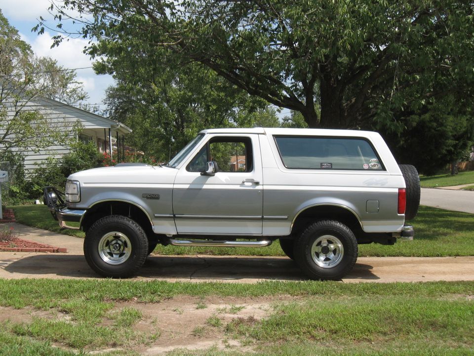Side view of a white and silver 1994 Ford Bronco with a spare tire on the back