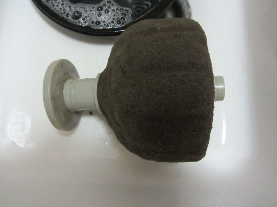 air filter with brown fuzzy cover, sitting in a sink with soap bubbles