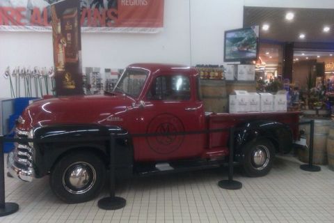 1991 Ford LTD Crown Victoria - A vintage red and black pickup truck is displayed indoors, possibly for a promotion.