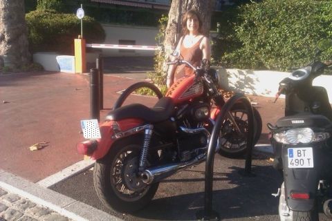 1991 Ford LTD Crown Victoria - A red Harley-Davidson motorcycle is parked next to a black Yamaha scooter, with a woman standing behind the motorcycle.