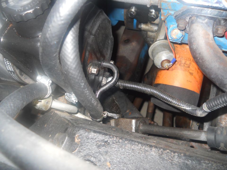 Engine bay showing hoses, oil filter, and metal components. Some text visible on filter