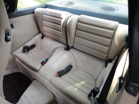 1986 Porsche 911 - The interior view shows the rear seating area of a car, with tan upholstery and seatbelts.