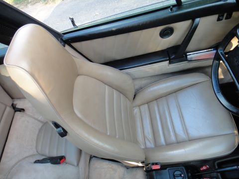 1986 Porsche 911 - Interior view of a car's tan leather seats and door panel, with a partial view of the steering wheel.