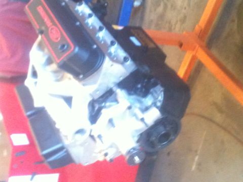 1993 Ford Bronco - Engine block assembly is shown on a stand, with some red material behind it.