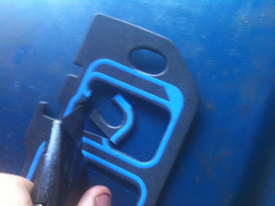 Black gasket with blue sealant, being cut by a utility knife