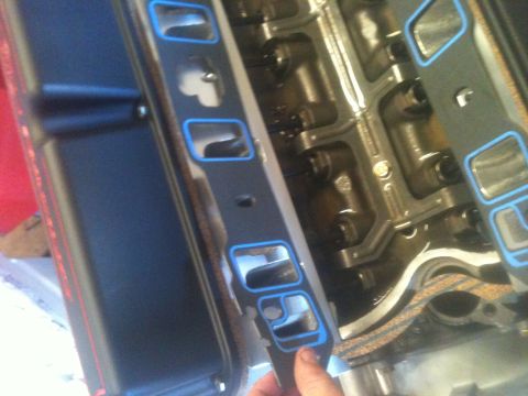 1993 Ford Bronco - Close-up of an engine intake manifold gasket being held near the engine block.