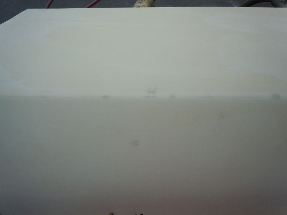 close-up of a light-colored car body panel, possibly primed for paint. Supermotors.net logo in lower right