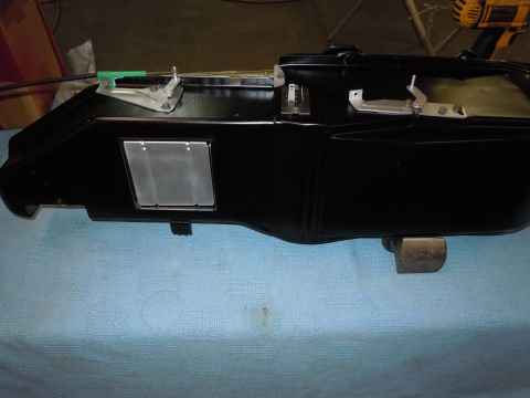 1973 Pontiac Trans Am - A black automotive part with visible metal hardware and a vent is shown against a blue background.